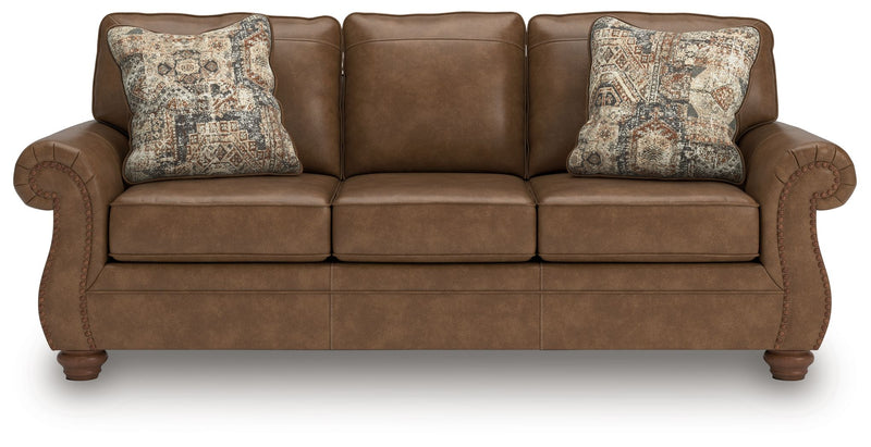 Brown sofa with three seat cushions and two patterned throw pillows