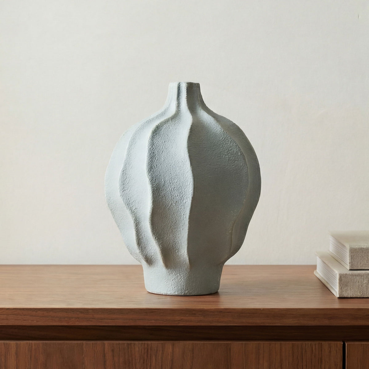 Blue ceramic vessel vase with textured surface, rounded body, narrow neck on table