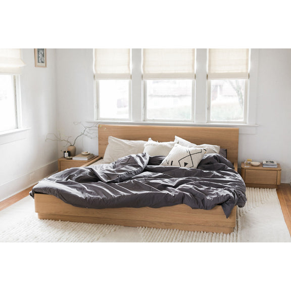 Natural oak king bed frame with panel headboard and mixed gray bedding