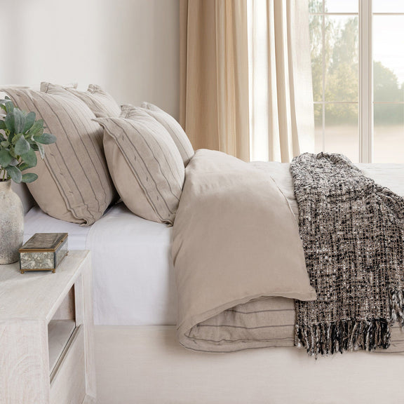 Striped bed sham pillow in light beige/ivory with vertical lines, layered with bedding.