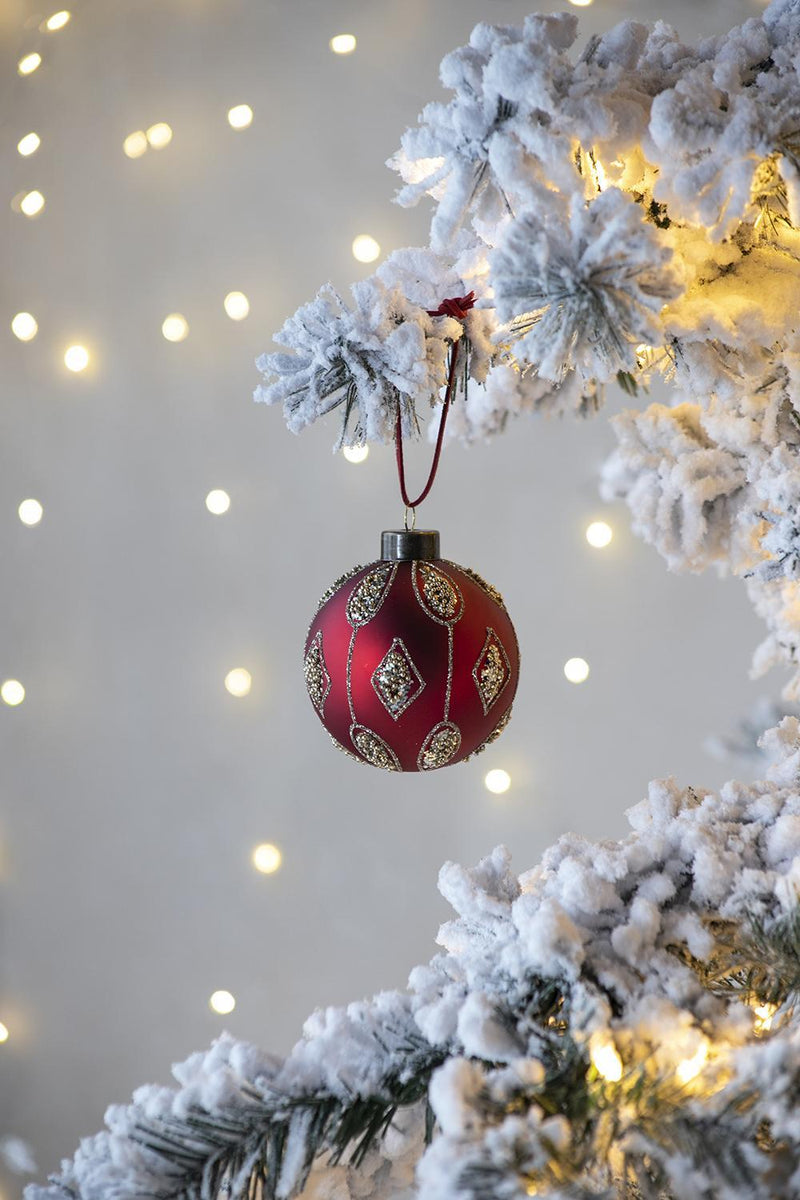 Red and gold Christmas ball ornament hanging on a tree branch, diamond and medallion details