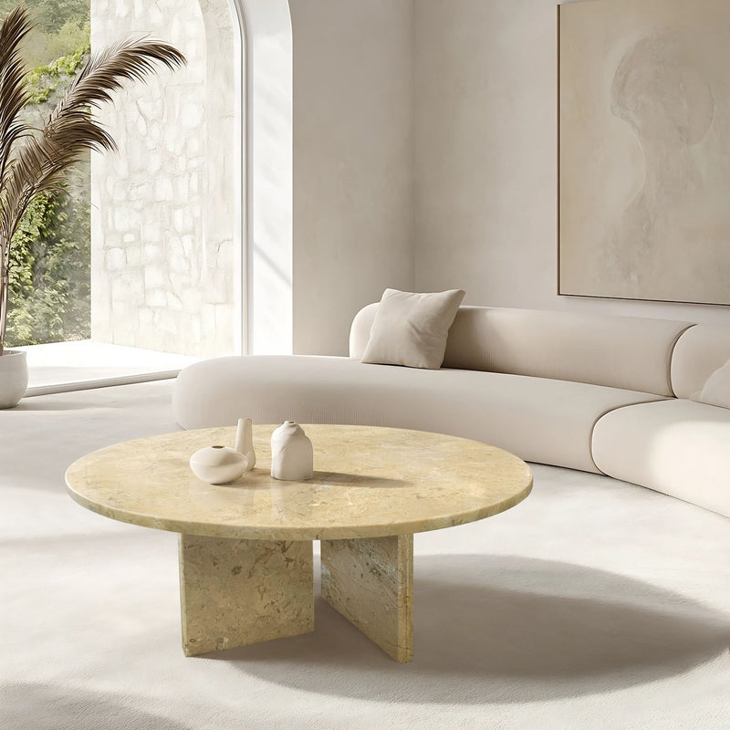 Round beige stone coffee table with unique veining, set in a modern seating area.
