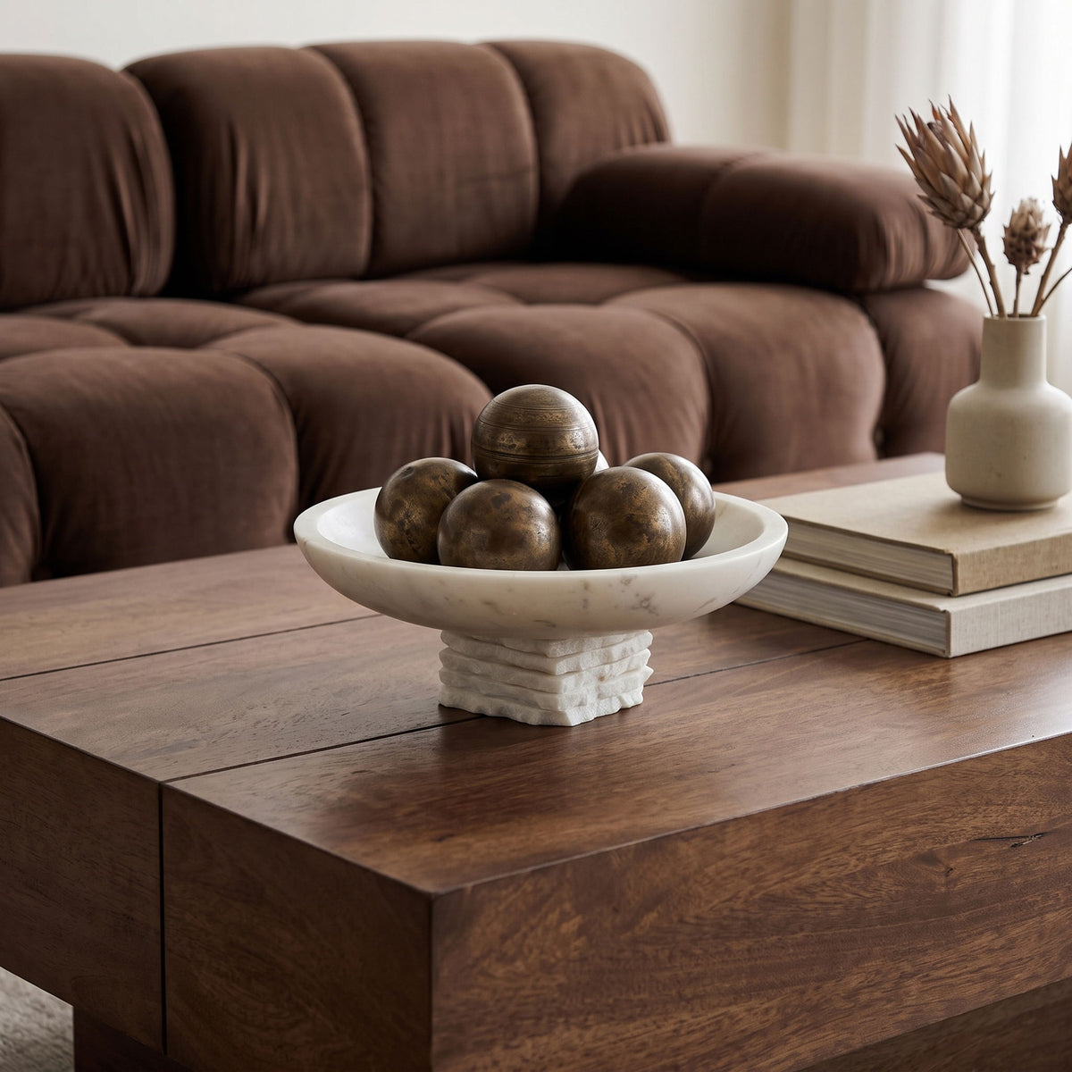 Genuine marble bowl centerpiece with white mottled basin and stacked pedestal on wooden coffee table.