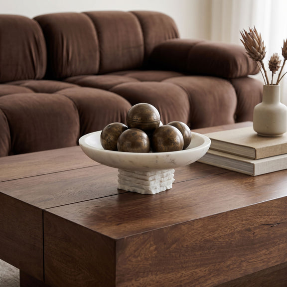 Genuine marble bowl centerpiece with white mottled basin and stacked pedestal on wooden coffee table.