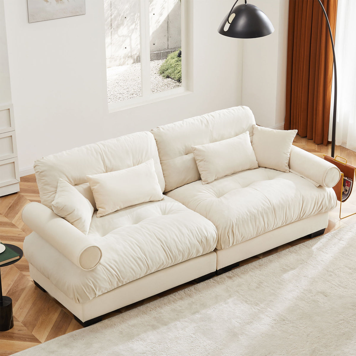 Beige upholstered sofa with tufted cushions, back throw pillows, and rounded bolster arms