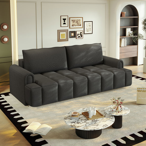 Black four-seat couch with broad arms and four segmented seat cushions, viewed from the front.