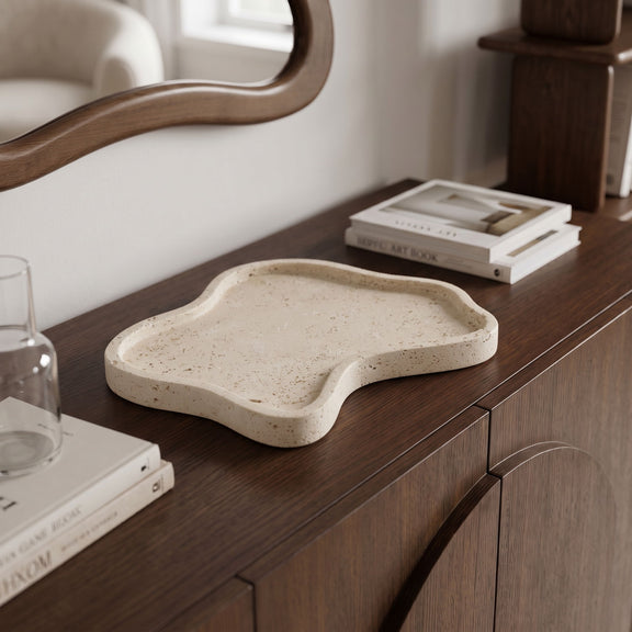 Beige speckled travertine serving tray with shallow center on a wooden table