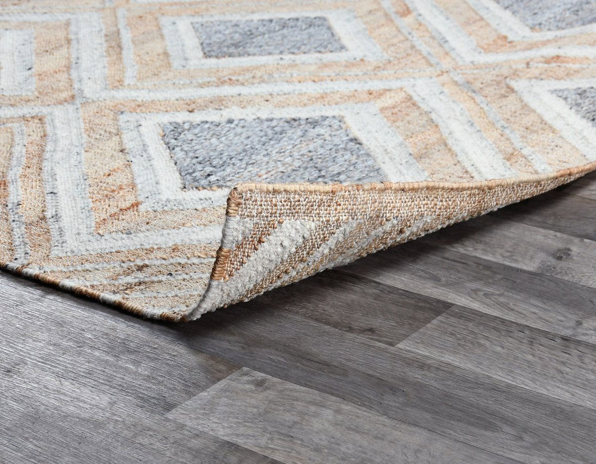 Geometric diamond rug corner with bound edge; textured low-pile surface