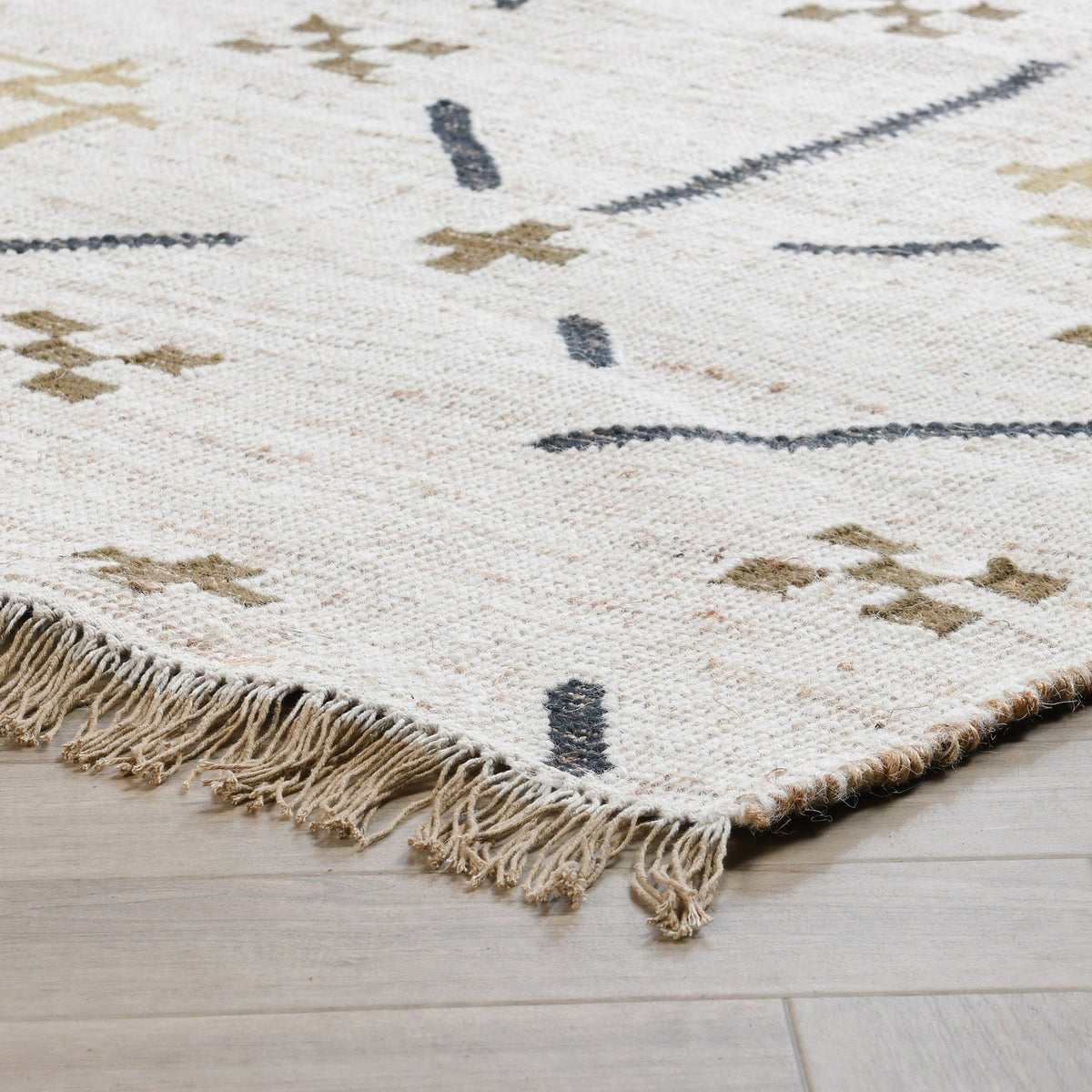 Ivory area rug with dark blue geometric motifs and short knotted fringe