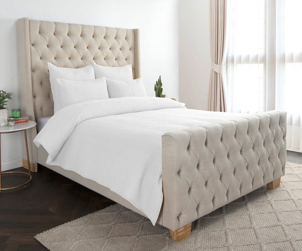 Light quilt set with matching shams, displayed on a bed with tufted headboard
