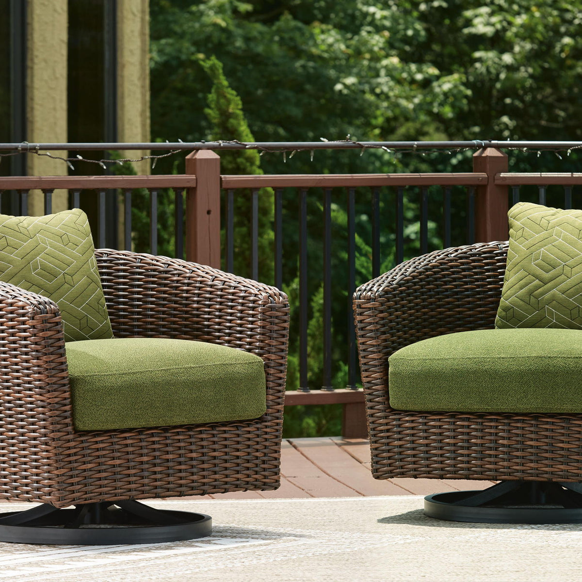Swivel lounge chairs with green cushions and dark brown wicker, shown as a pair
