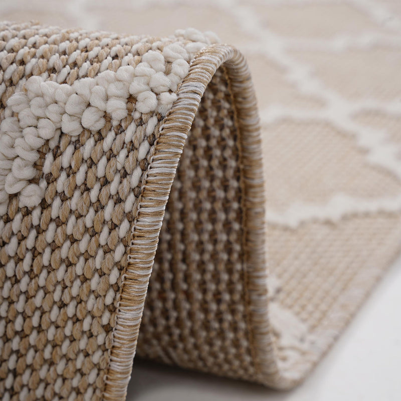 Close-up of beige rug edge with braided border and raised loop texture.