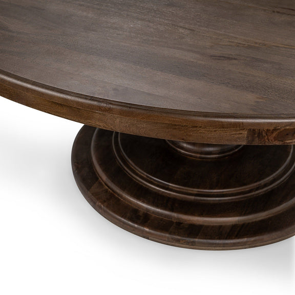 Dark brown round dining table with pedestal base and curved apron