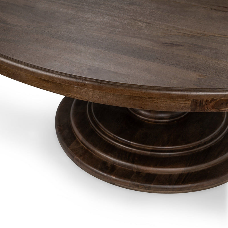 Dark brown round dining table with pedestal base and curved apron