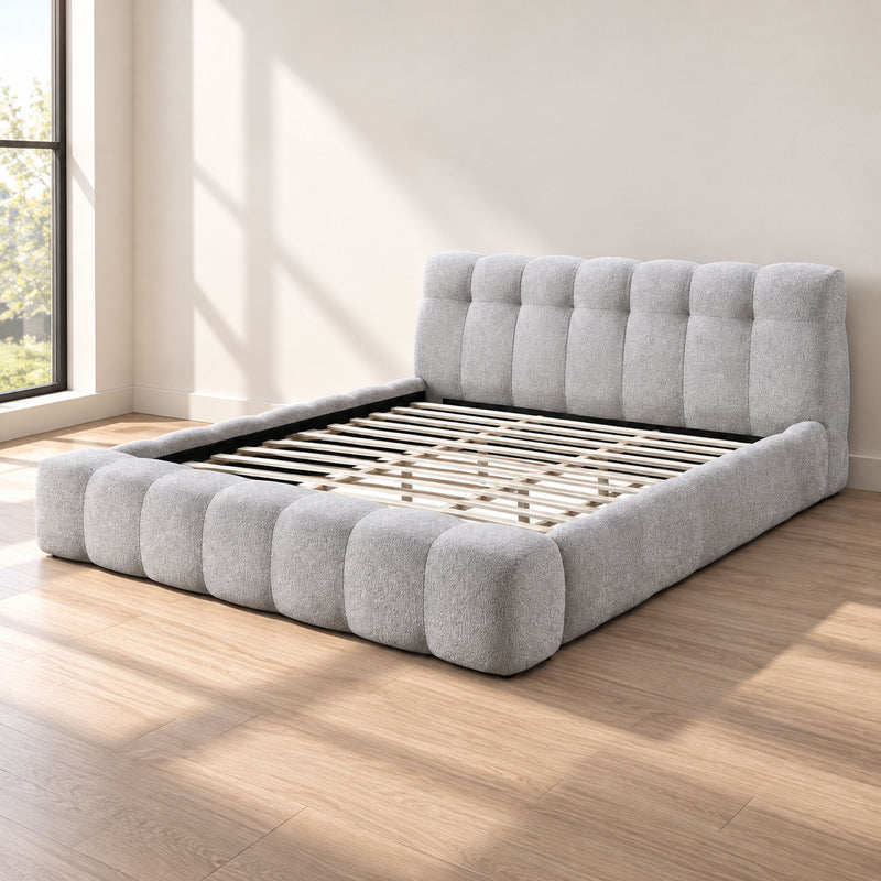 Gray Eastern king upholstered bed with tall headboard and black slat foundation on platform