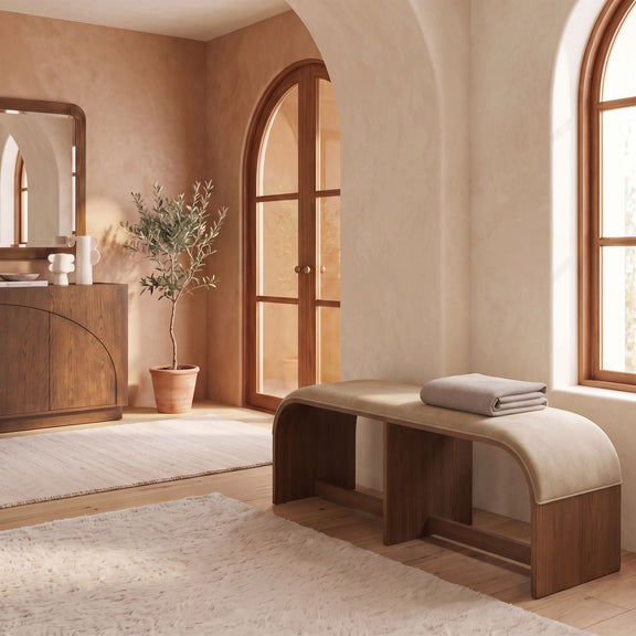Beige velvet upholstered bench with dark wooden frame in a room setting