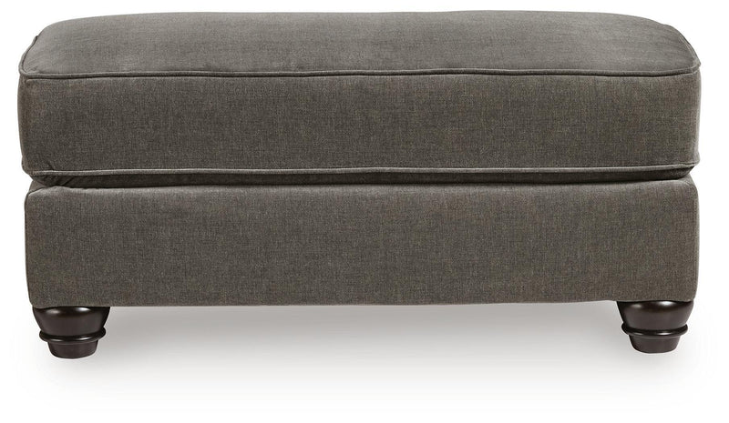 Dark gray fabric ottoman with low profile base and turned legs