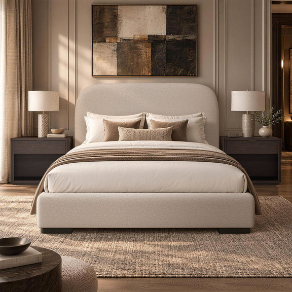 Beige upholstered bed with rounded headboard and neatly styled pillows and blanket