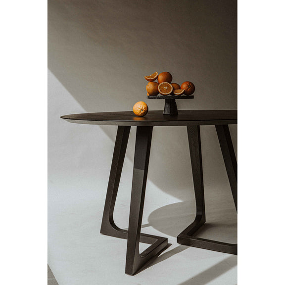 Round dining table with dark round top and tapered pedestal legs with X braces