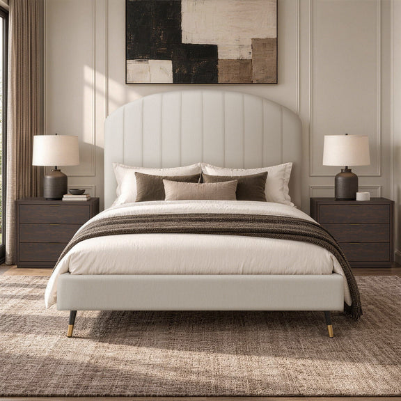 Beige arched upholstered bed with white duvet and brown throw blanket