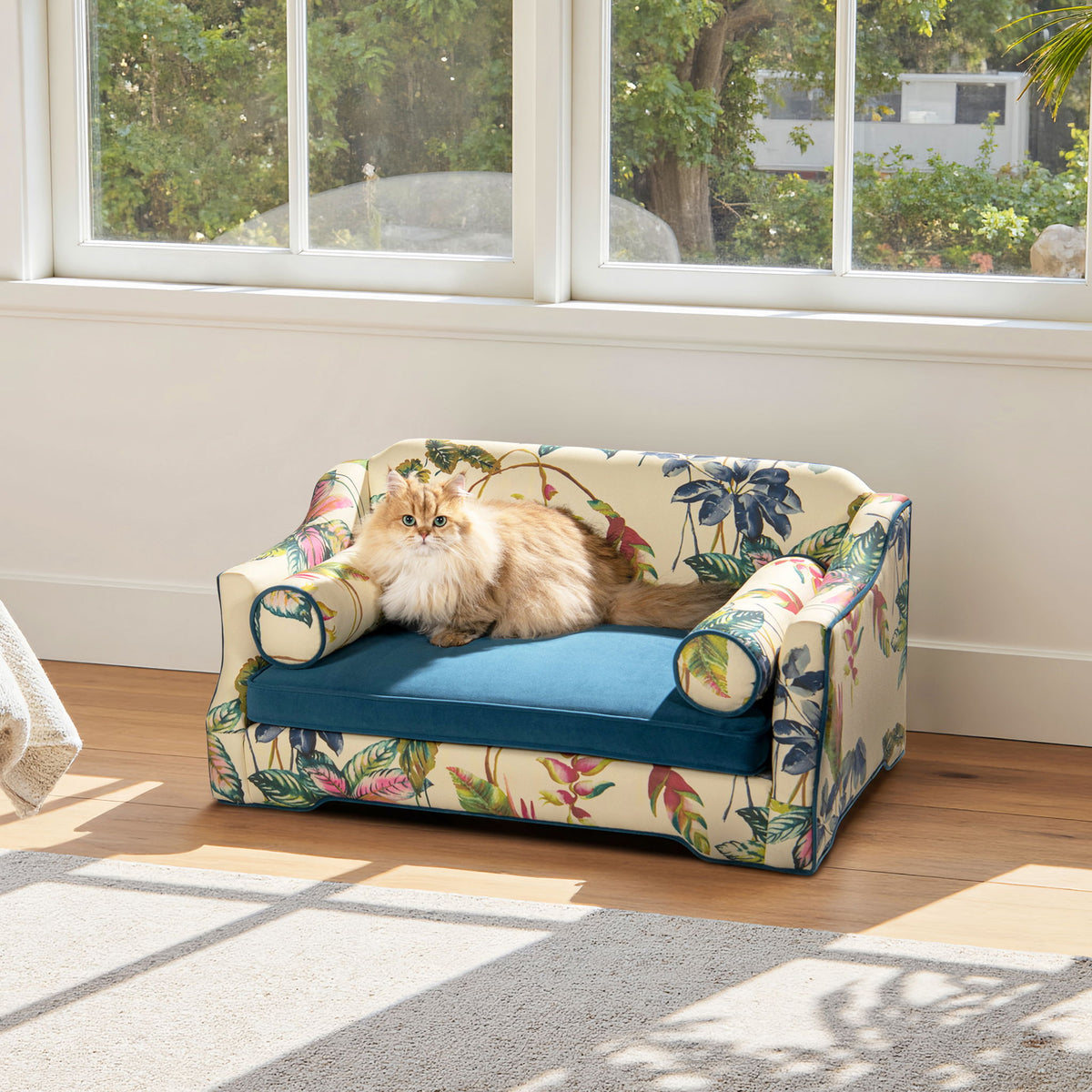 Floral-pattern dog sofa bed with blue cushion, rounded arm bolsters, and padded sides