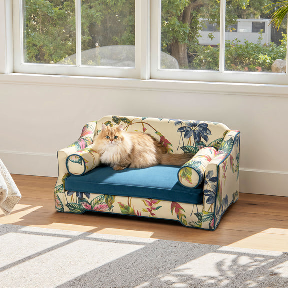 Floral-pattern dog sofa bed with blue cushion, rounded arm bolsters, and padded sides