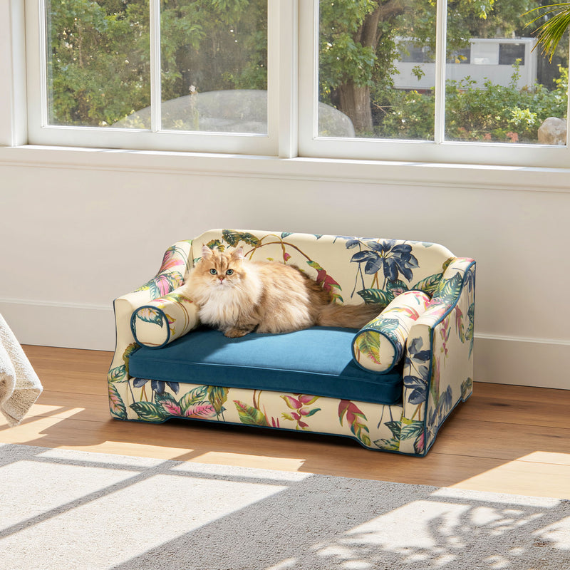 Floral-pattern dog sofa bed with blue cushion, rounded arm bolsters, and padded sides