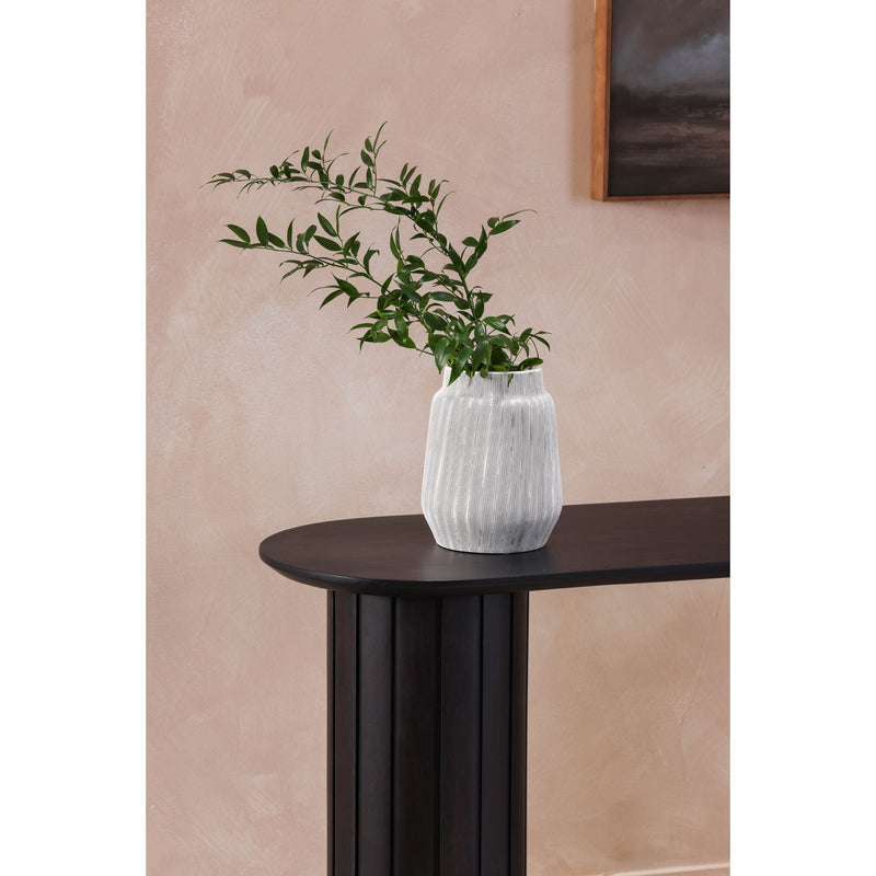 Black console table with oval top and fluted pedestal legs, with vase and greenery