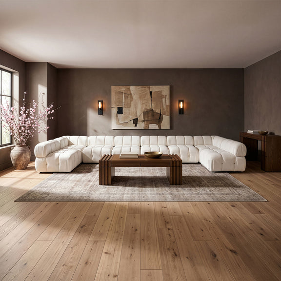 White modular sectional sofa with padded, tufted cushions and curved corner layout