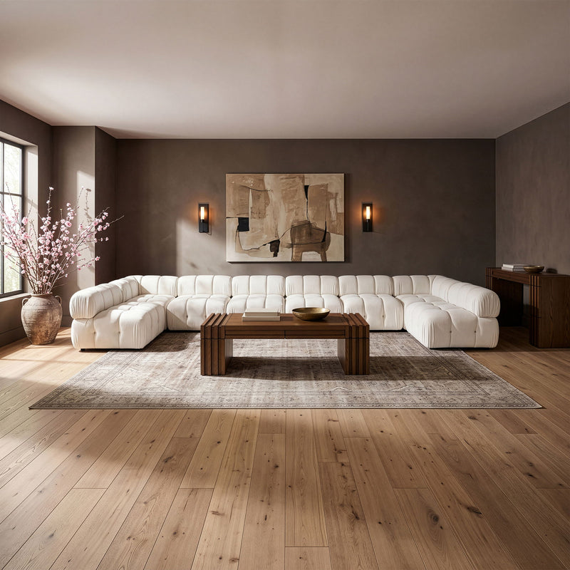 White modular sectional sofa with padded, tufted cushions and curved corner layout