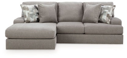 Gray sectional sofa with corner chaise, three seat cushions and patterned accent pillows.