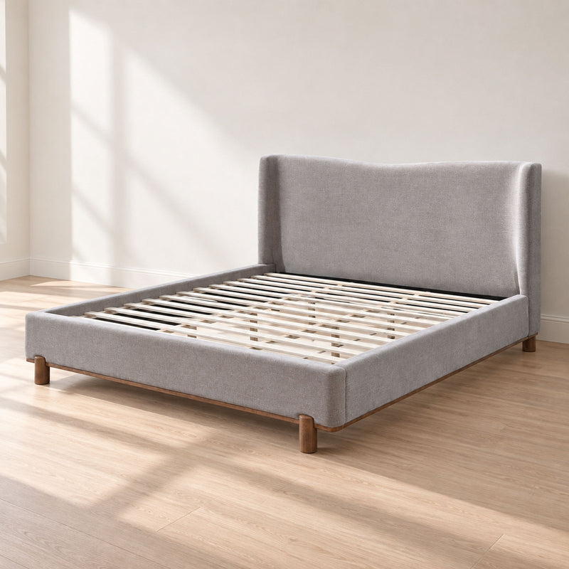 Gray upholstered bed frame with slatted base and low platform sides, wooden feet