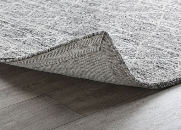 Corner view of ivory and gray rug with stitched hem and fabric backing