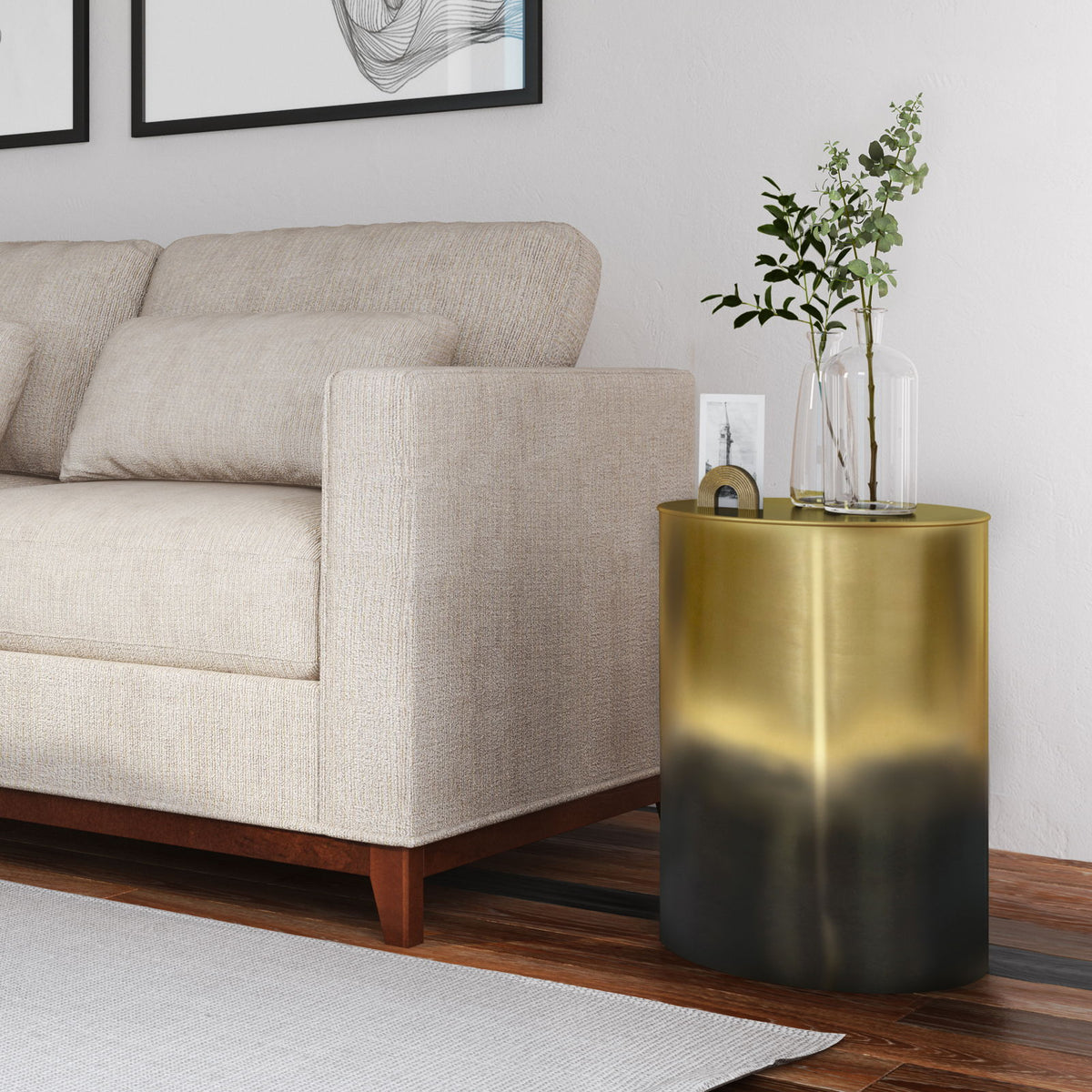 Gold-to-black ombre metal cylinder accent table with round top beside sofa