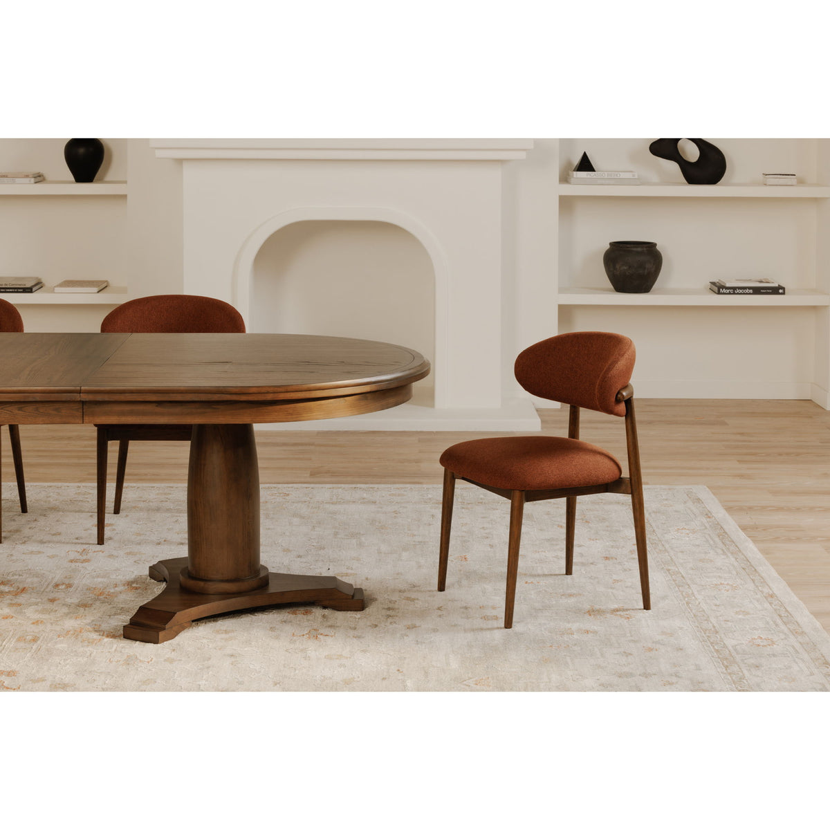 Rust upholstered dining chair with rounded back, curved seat, wooden legs
