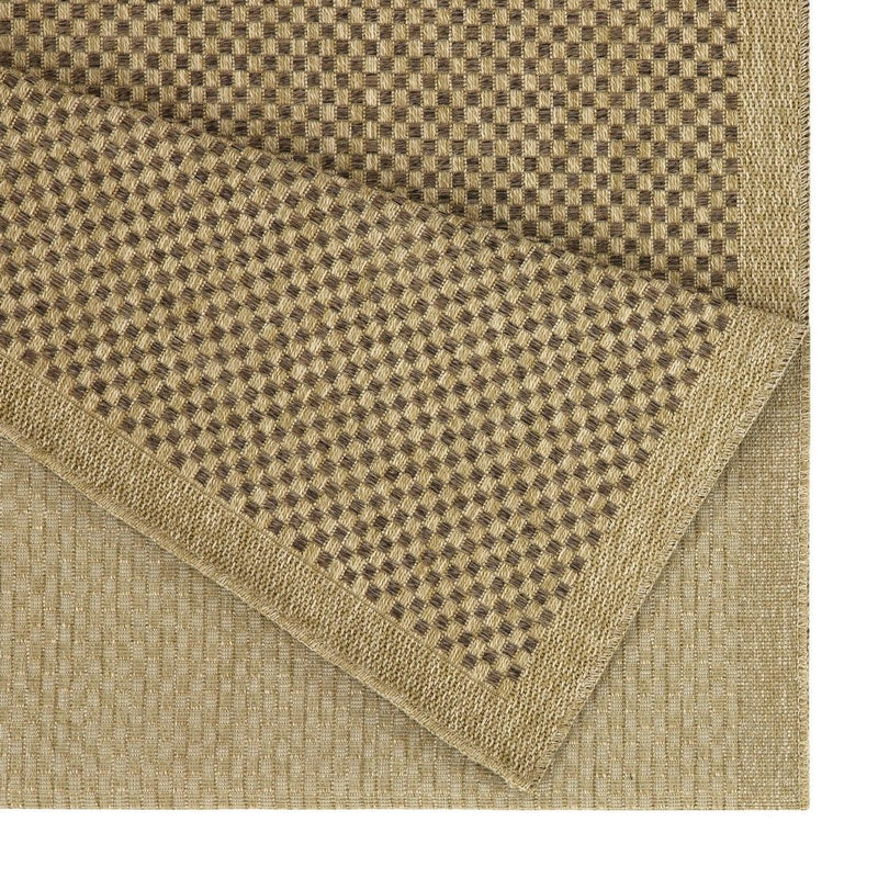 Corner detail of light brown polypropylene rug with checkered weave and stitched edge