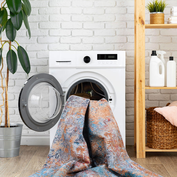 Washable area rug draped on front-load washer, blue and orange abstract speckle