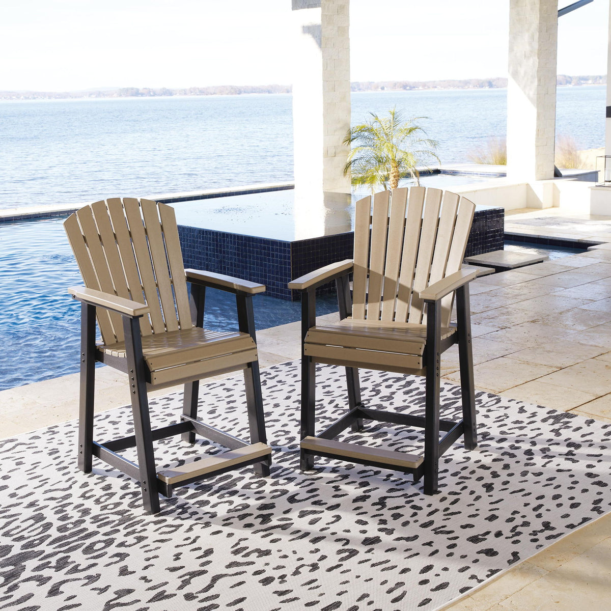 Two driftwood barstools with black frames, slatted backs, and armrests on patio