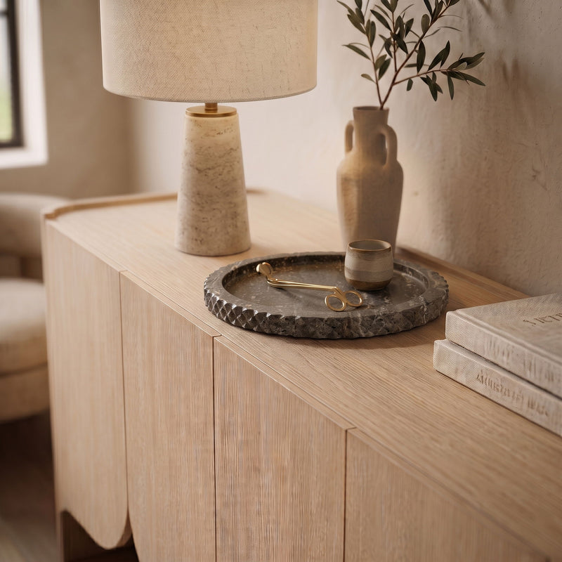 Gray travertine tray on wooden dresser holding small brass scissors and tools.