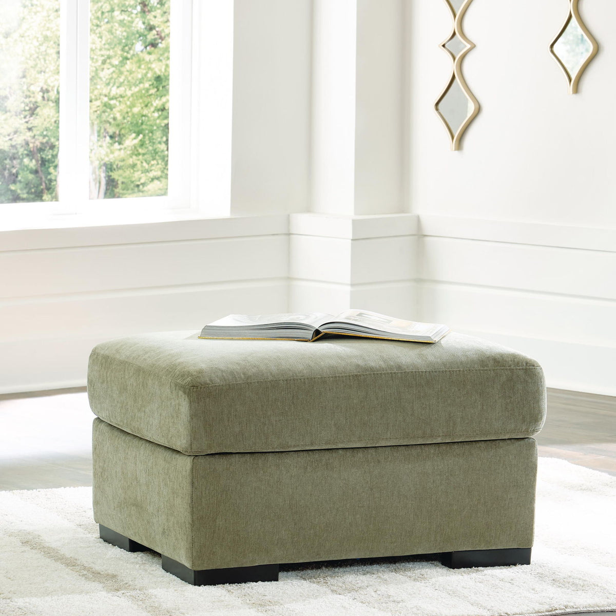 Green fabric ottoman with rounded seat and dark block feet