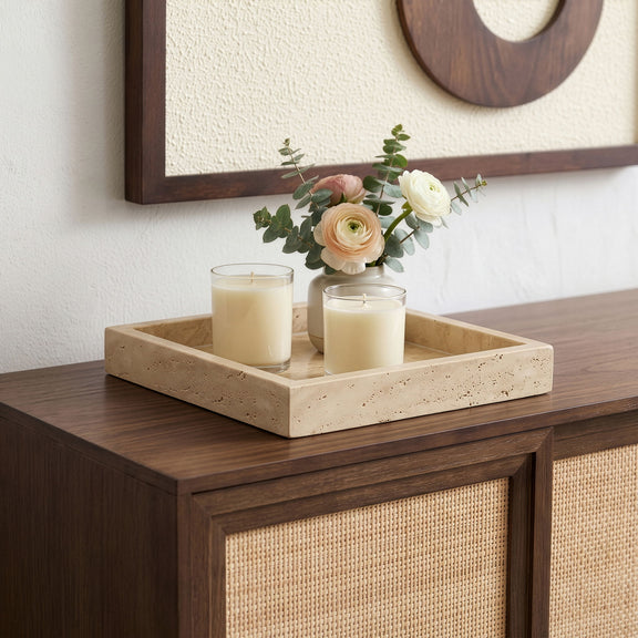 Beige travertine tray holding two candles and a small floral arrangement