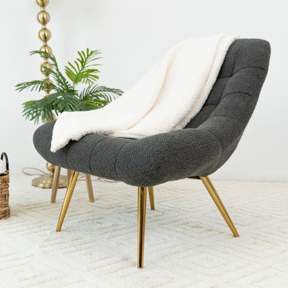 Dark gray boucle lounge chair with curved arms, tufted seat, and gold-tone legs