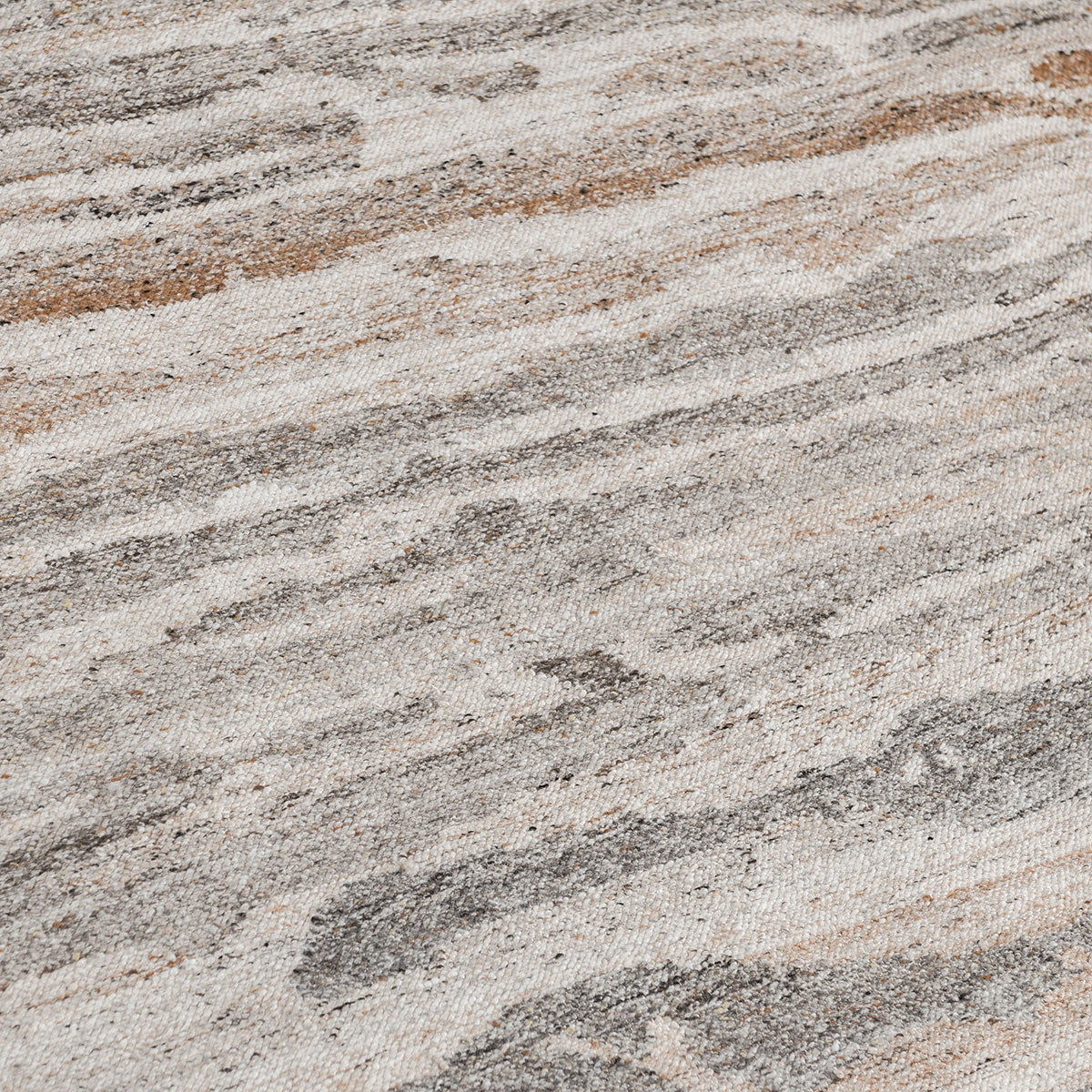 Close-up of abstract woven rug texture in cream, tan, and gray with mottled fibers