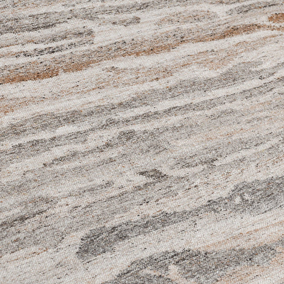 Close-up of abstract woven rug texture in cream, tan, and gray with mottled fibers