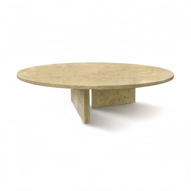 Round beige stone coffee table with sculpted base and visible natural veining.