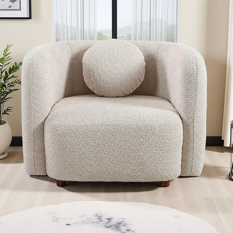 Beige boucle accent chair with round throw pillow, curved arms, and short wooden legs.