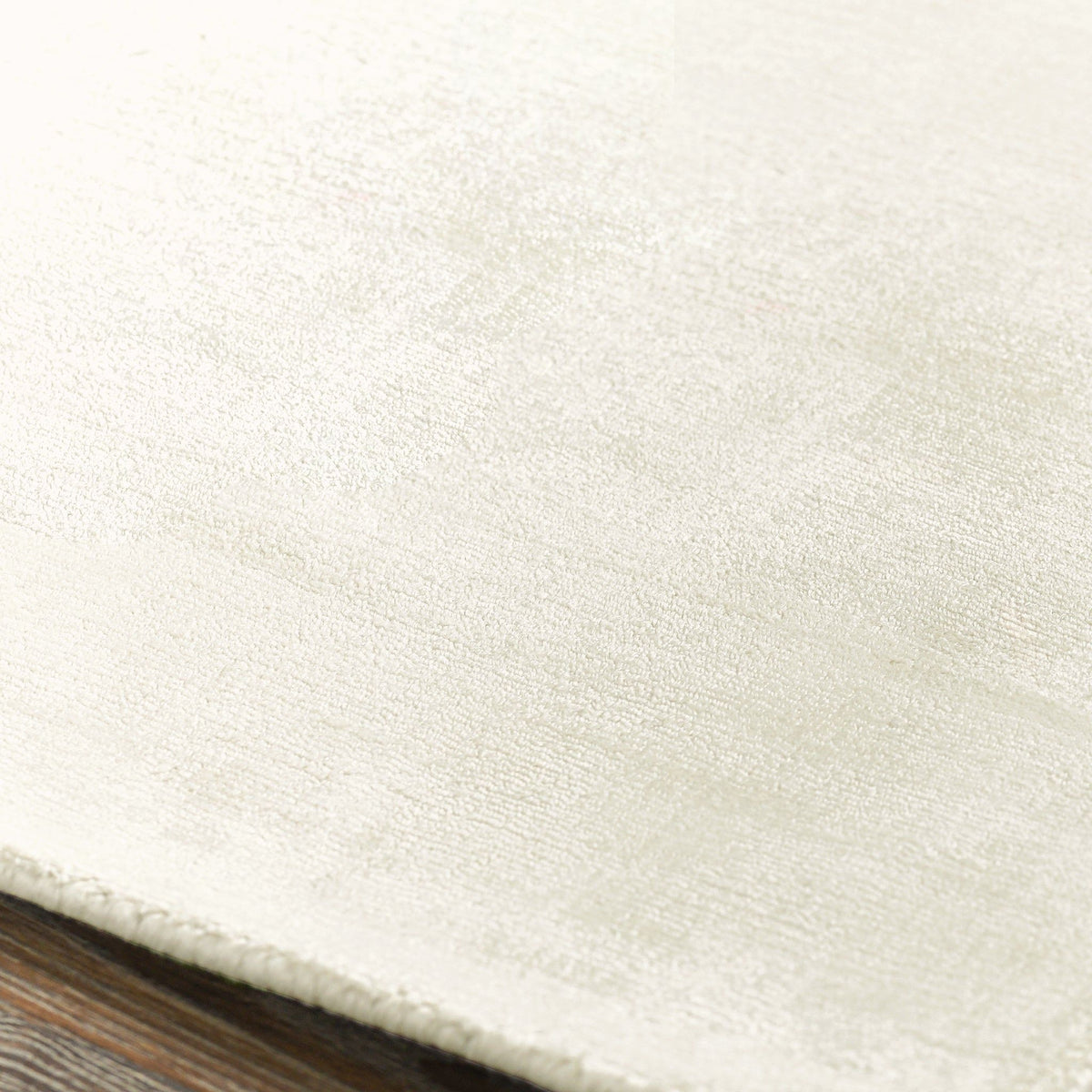 Ivory distressed area rug with fine textured surface and low, flat pile.