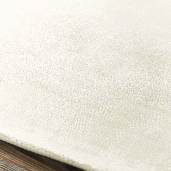 Ivory distressed area rug with fine textured surface and low, flat pile.