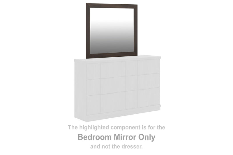 Rectangular dark brown bedroom mirror resting on white cabinet