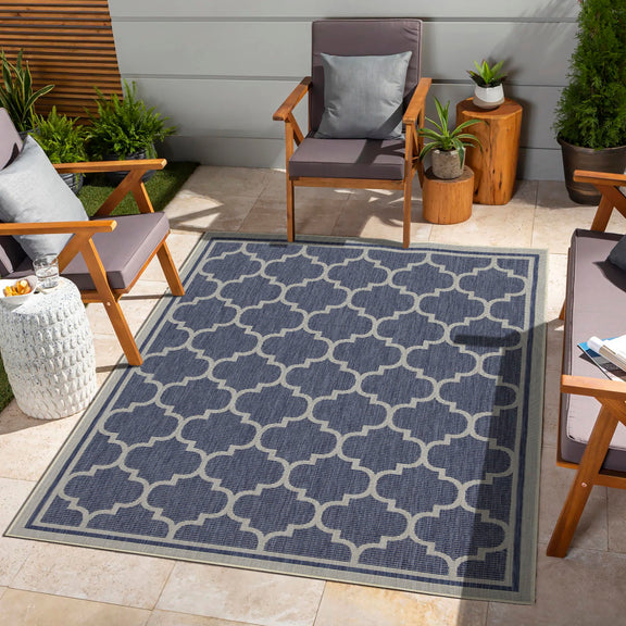 Blue polypropylene area rug with repeating quatrefoil pattern and bordered edges